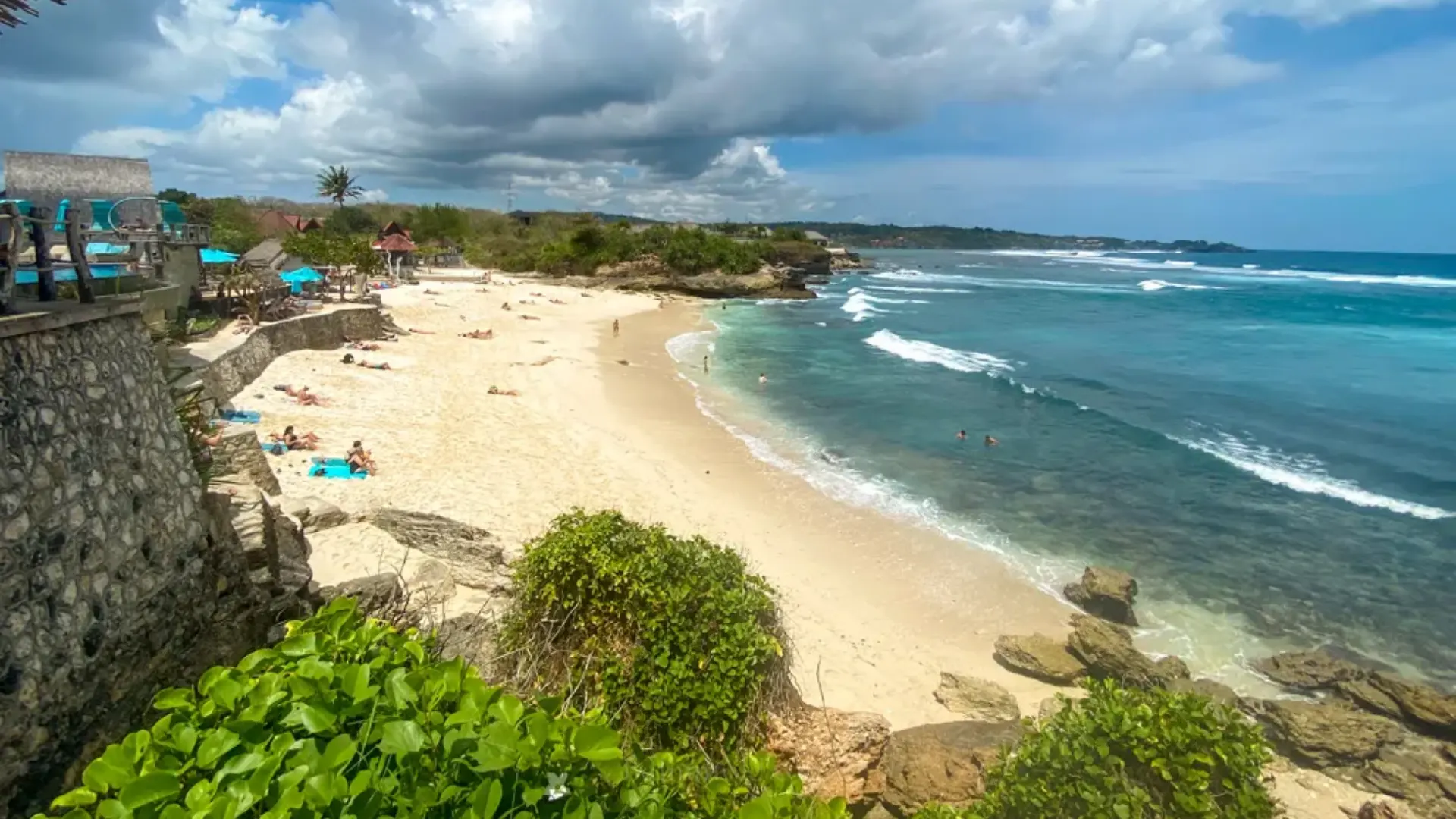 White sand shoreline and turquoise waves at Dream Beach Nusa Lembongan, viewed from the cliffside during a sunny day.