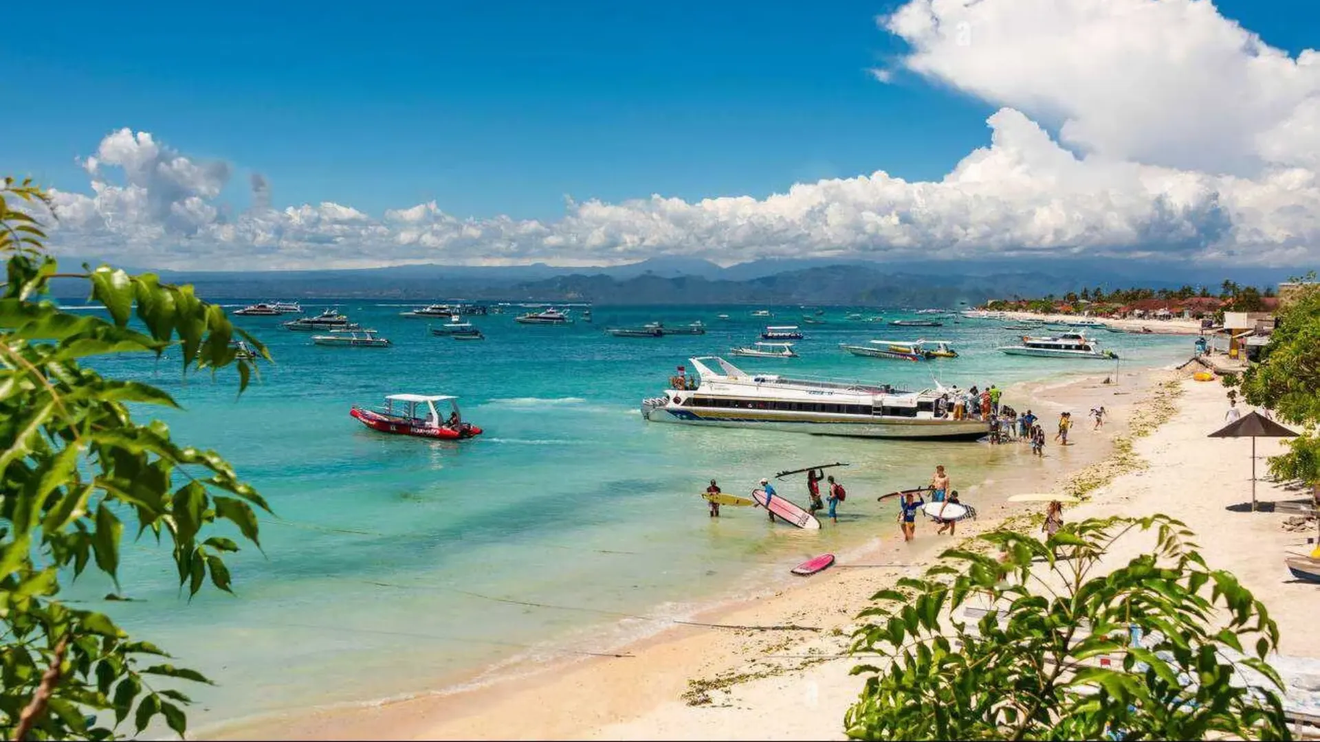 Traditional wooden boats and speedboats anchored in the shallow turquoise water of Jungut Batu Beach Nusa Lembongan.
