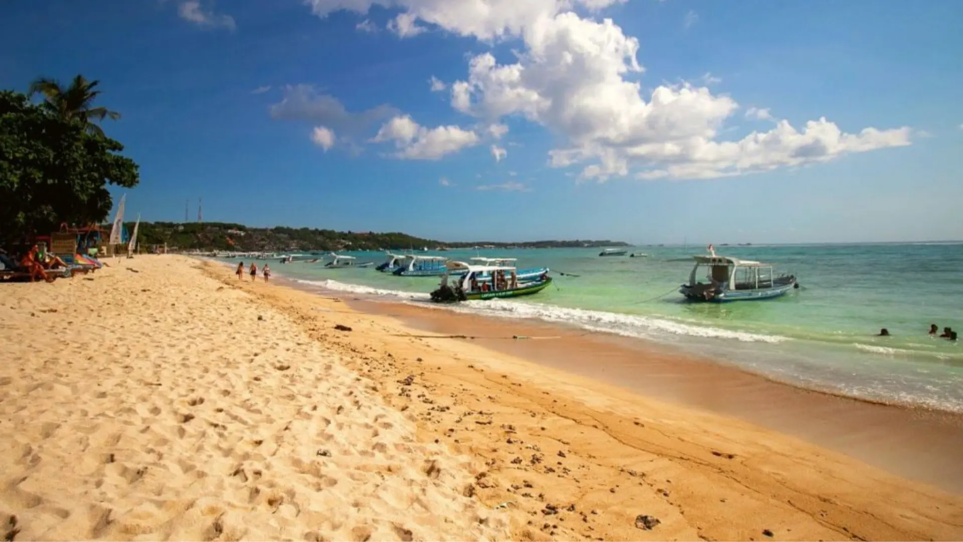 Wide sandy shoreline of Jungut Batu Beach Nusa Lembongan with traditional boats moored near the local village.